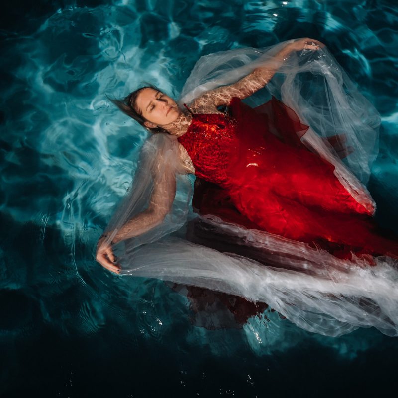 A girl in a red dress is floating on the water.A journey on the water of a single woman.
